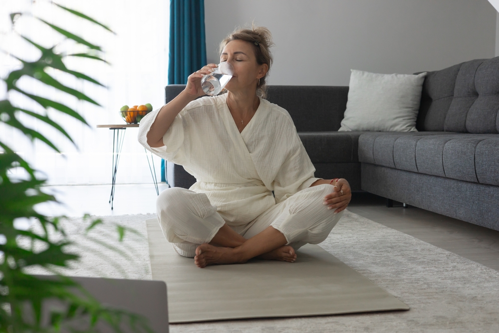 femeie pe saltea, facand yoga si band apa